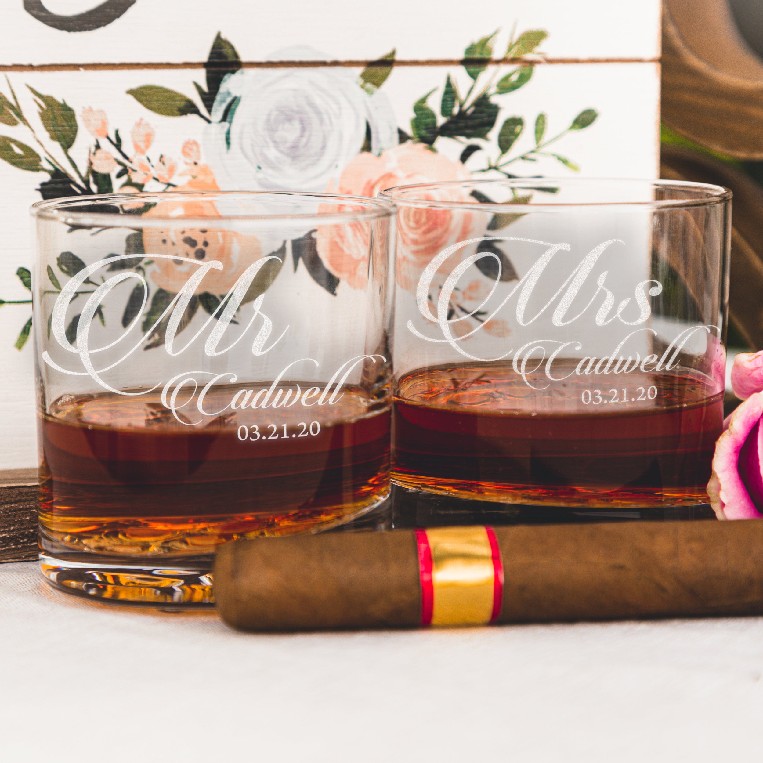 Whiskey glass on a table. The glass has an etched design centered on the front. The design is "Mr" in cursive and below it is "Cadwell" in cursive then below that is "03.21.20". The design is centered and can be "Mr" or "Mrs".